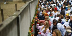 Na Bernauer Strasse, uma rua em Berlim, pessoas colocam flores no que sobrou do Muro de Berlim durante uma comemoração de sua queda em 2019 (© Markus Schreiber/AP)